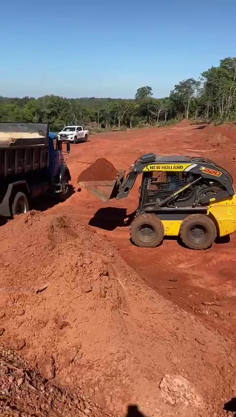 Mini carregadeira carregando caminhão basculante