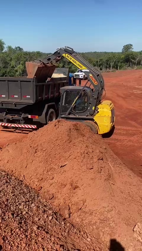Mini carregadeira carregando terra em caminhão